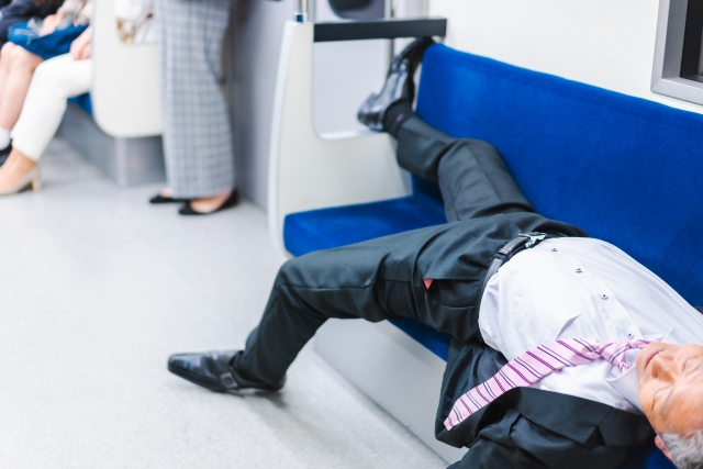 電車内で寝転ぶ中年男性